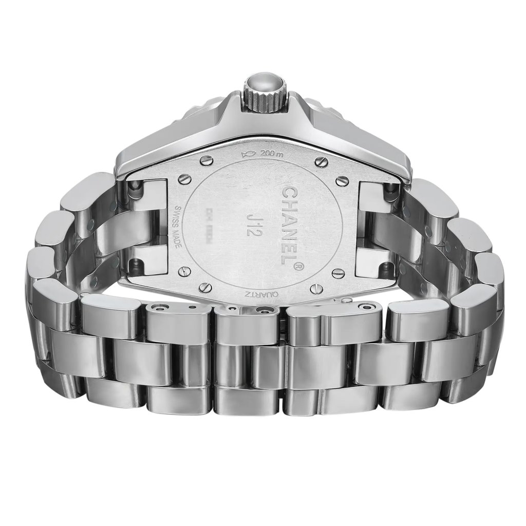 An image of a pre-owned Chanel J12 wristwatch viewed from the back, showing a ceramic caseback with a screwback mechanism, and a ceramic band with a double fold-over clasp. The round watch is positioned upright with the clasp open and visible in the foreground, viewed at a close distance, emphasizing the watch's shape and clasp detail. The case and band exhibit light scratches and signs of wear.