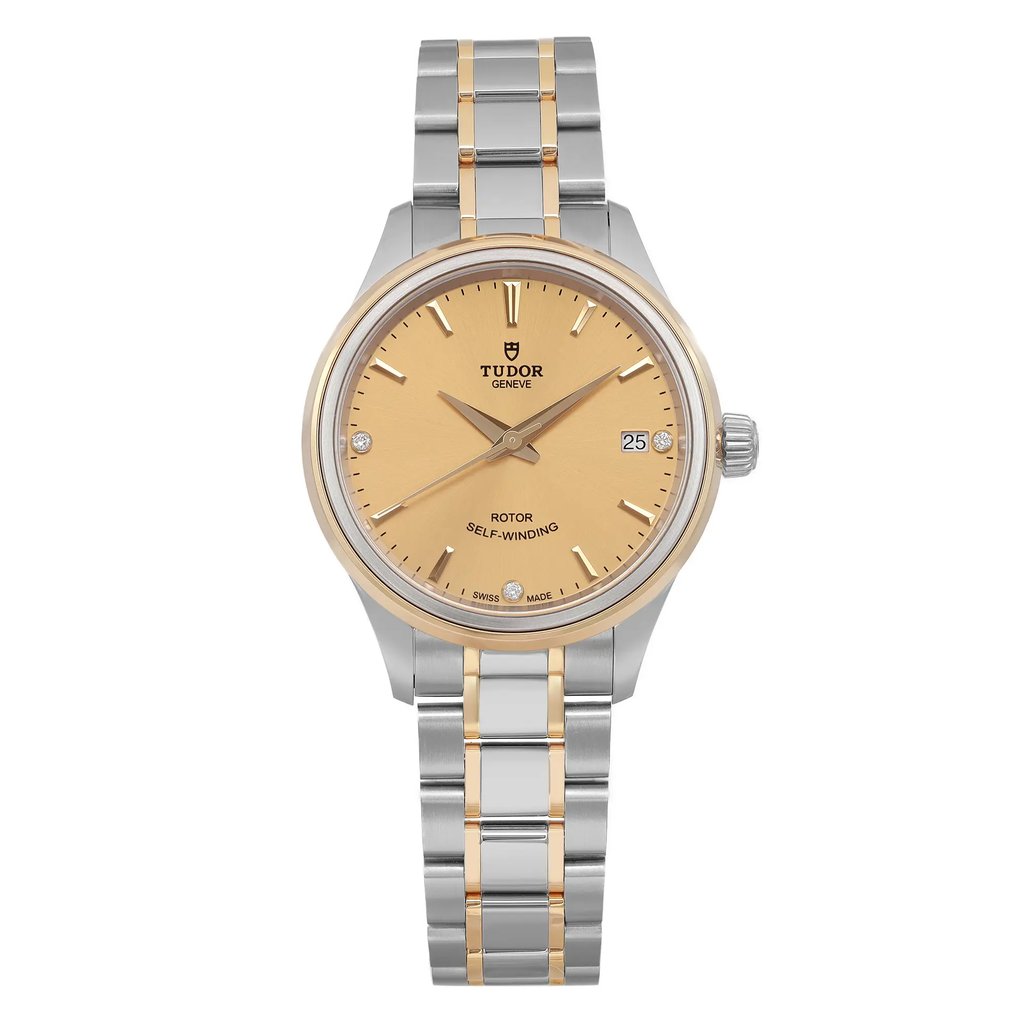 An image of a women's unworn TUDOR Style 34mm wristwatch taken from a front-facing angle at close distance. The watch features a two-tone stainless steel and gold bracelet and a champagne dial with a date indicator located at the 3 o'clock position. The watch hands and hour markers are clearly visible, highlighting the elegant design.