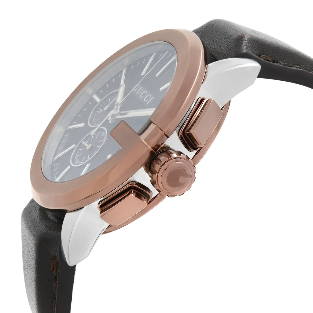 An image of a new Gucci wristwatch for men with defects, shown from a close-up side angle highlighting its rose gold case and crown, grey dial with Gucci logo, chronograph features, luminous hands, and a small seconds subdial. The watch is attached to a dark grey leather strap, partly visible, pointing towards the bottom right of the frame.