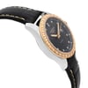 An image of a wristwatch taken from a side profile view, showcasing the opposite side of the crown. The watch features a black leather strap with visible stitching. The case is silver with a gold bezel adorned with small diamonds. The dial is black with gold hands and diamond hour markers. The photo is taken at a slight upward angle, highlighting the watch's elegant design and luxurious details.