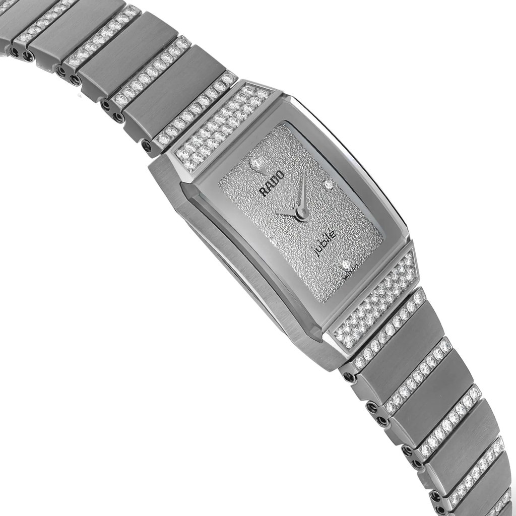 An image of an unworn Rado women's luxury wristwatch with a side profile view opposite of the crown. The watch features a silver dial and bezel, with a white gold band and case. The rectangle-shaped watch is captured in close-up, showing the left side angle, highlighting the smooth finish and sparkling embellishments along the band and dial area.