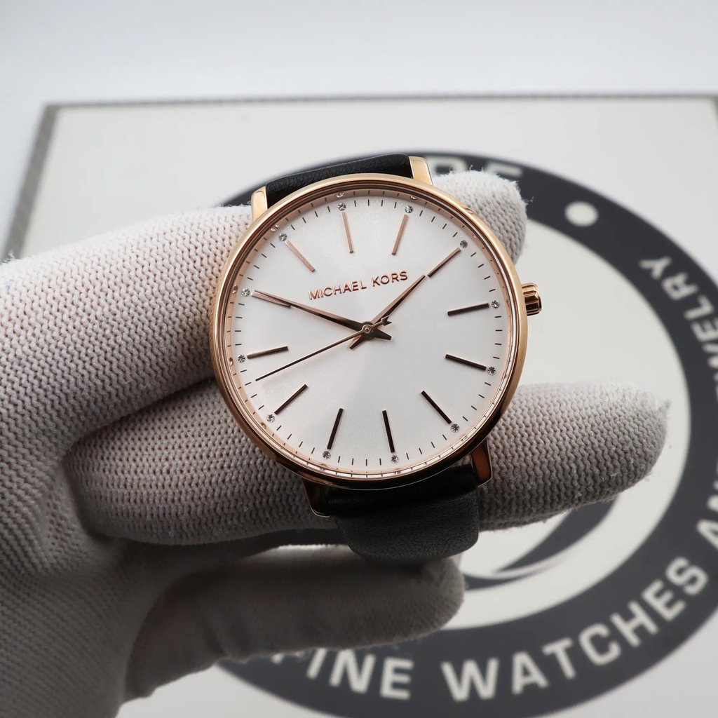 An image of a Wristwatch by Michael Kors. This Display Model item is designed for Women, featuring a Dress/Formal style. It has a Quartz movement and an Analog display with a Silver dial color. The indices include 12-Hour Dial,Stick Indexes. The band is made of Leather and the case is made of Stainless Steel. The watch has a Round shape with a case size of 38 mm and a case thickness of 7 mm.
