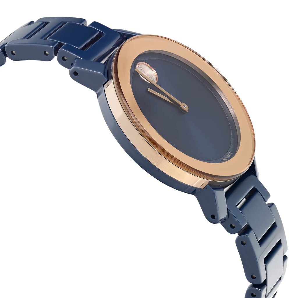 An image of a wristwatch taken from a side profile view opposite the crown, showcasing the sleek design. The watch features a smooth, round face with a gold-toned bezel and deep blue dial. The bracelet is a matching blue with a glossy finish. The angle highlights the watch's elegant curves and the seamless integration of the band with the case. The photograph is taken at a close distance, emphasizing the details of the watch's construction and finish.