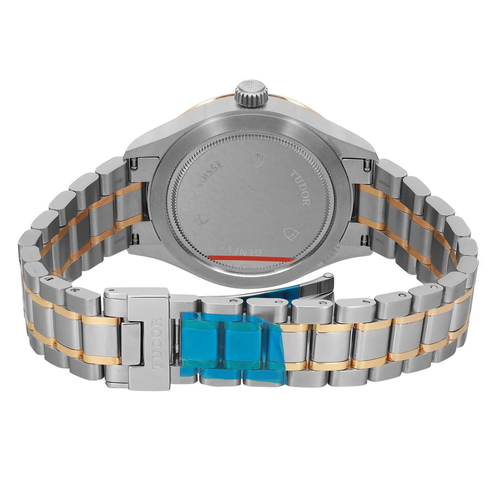 An image of a wristwatch shown from the back view, highlighting the closed clasp. The watch is unworn, with a two-tone metal bracelet featuring both silver and gold links. The close-up angle emphasizes the details on the case back and the clasp area, which is partially covered with blue protective film. The brand name is subtly engraved on the clasp.