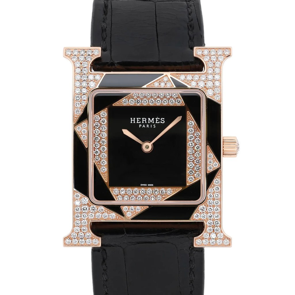 An image of a pre-owned women's Hermès wristwatch shown from a front-facing view. The watch features a square black dial with delicate rose gold hands and is adorned with geometric patterns encrusted with sparkling diamonds. The black leather strap is visible at the top and bottom, adding elegance to the luxurious design. The photograph captures the watch at a close distance, highlighting the intricate details and craftsmanship.