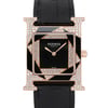 An image of a pre-owned women's Hermès wristwatch shown from a front-facing view. The watch features a square black dial with delicate rose gold hands and is adorned with geometric patterns encrusted with sparkling diamonds. The black leather strap is visible at the top and bottom, adding elegance to the luxurious design. The photograph captures the watch at a close distance, highlighting the intricate details and craftsmanship.