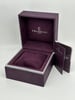 An image of a wristwatch box from Charriol, viewed from a slightly elevated angle. The box is open, showcasing its plush, dark purple interior with the brand name "CHARRIOL" and "GENEVE" printed on the inside back. In front of the box, there is a matching booklet partially visible. The box is positioned centrally, and the photo captures it up close, filling most of the frame.