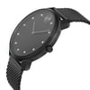 An image of a wristwatch from a side profile view, showing the crown prominently. The watch has a sleek black design with a mesh strap and a minimalist face featuring simple hour markers. The angle highlights the watch's thin profile, and the photograph is taken at a close distance to capture details, emphasizing its modern style despite being new with defects.