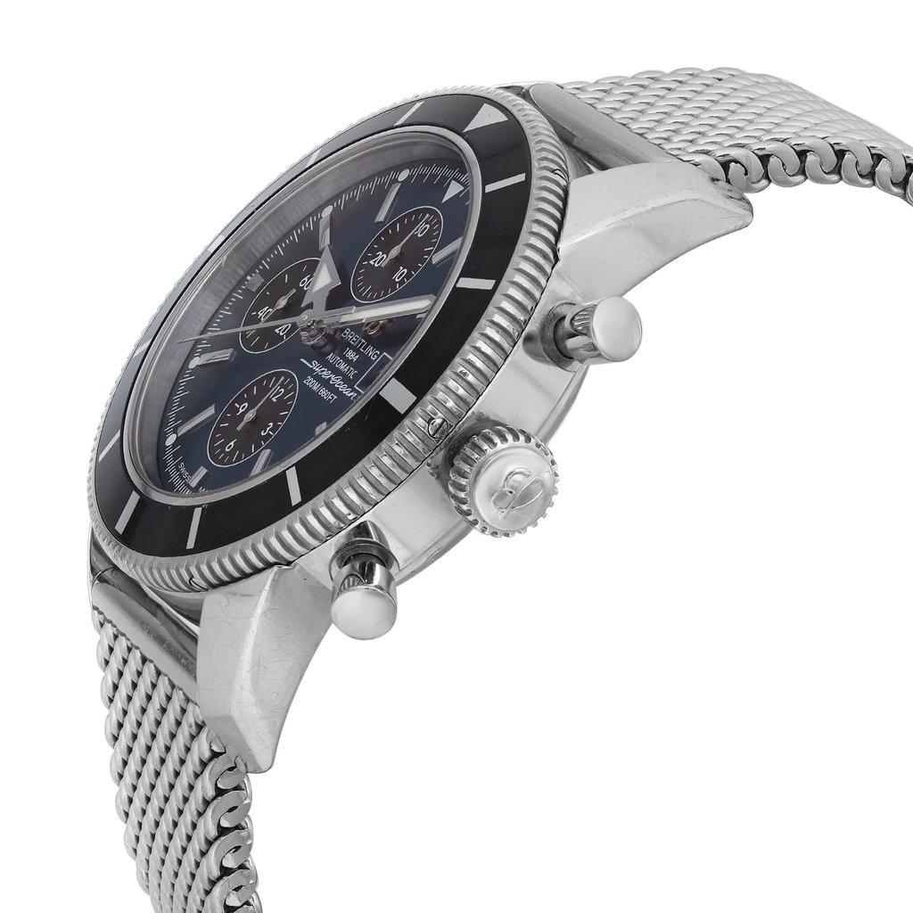 An image of a pre-owned Breitling men's wristwatch with a casual style, captured from a side profile angle showing the crown. The watch features a round stainless steel case and band, with a sunburst blue dial and black bezel. It includes a chronograph, date indicator, luminous hands, and a small seconds subdial. Visible scratches can be seen on the bezel insert, and minor nicks are present on the case and case back. The photograph is taken at a close distance, emphasizing the watch's details and signs of wear.