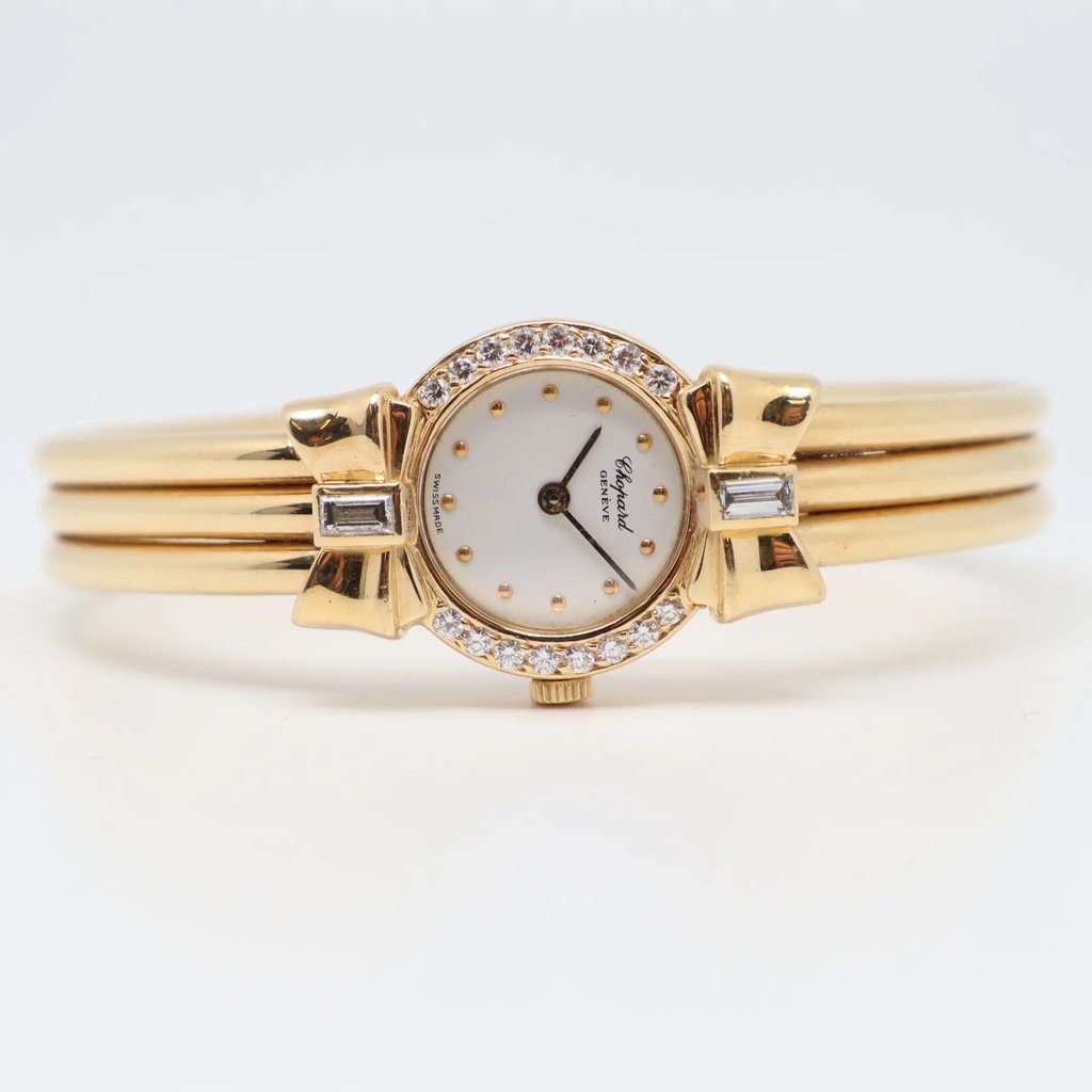 An image of a Wristwatch by Chopard. This Pre Owned item is designed for Women, featuring a Luxury style. It has a Quartz movement and an Analog display with a White dial color. The indices include Dots. The band is made of Yellow Gold and the case is made of Yellow Gold. The watch has a Round shape with a case size of 19 mm and a case thickness of 5 mm.