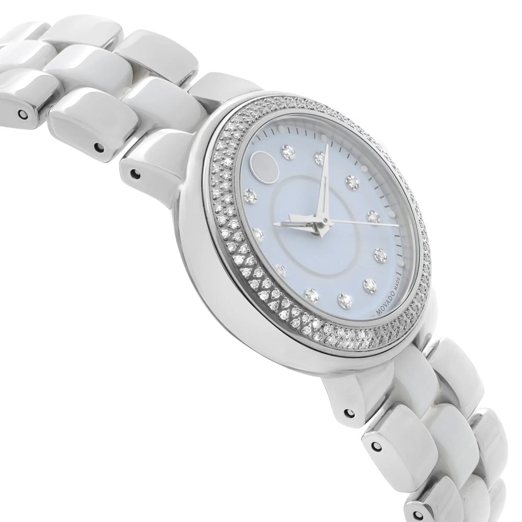 An image of a pre-owned wristwatch is shown from a side profile view, opposite the crown. The angle highlights the watch's round face and bezel adorned with sparkling stones. The watch's bracelet is visible, featuring a series of polished links. The photograph is taken from a close distance, capturing the details of the watch's design and construction.