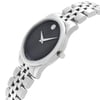 An image of a wristwatch captured from a side profile view, highlighting the crown on the right side. The watch features a sleek, silver-toned case and a black dial with minimalist hour and minute hands. Its stainless steel bracelet is visible, showcasing a polished finish. The angle emphasizes the elegant curvature of the watch, and the image is taken from a close distance to highlight the details of the display model.