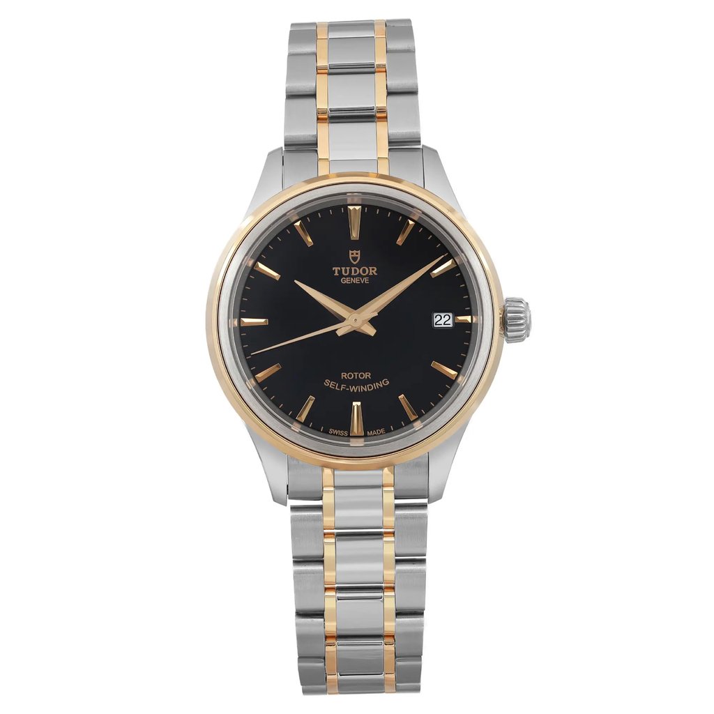 An image of a TUDOR Style 34mm women's wristwatch, displayed from a front-facing angle at a close distance. The watch features a black dial with yellow gold hour markers and hands, along with a date indicator at the 3 o'clock position. The bezel is gold, complementing the two-tone steel and gold bracelet. The watch is in unworn condition.