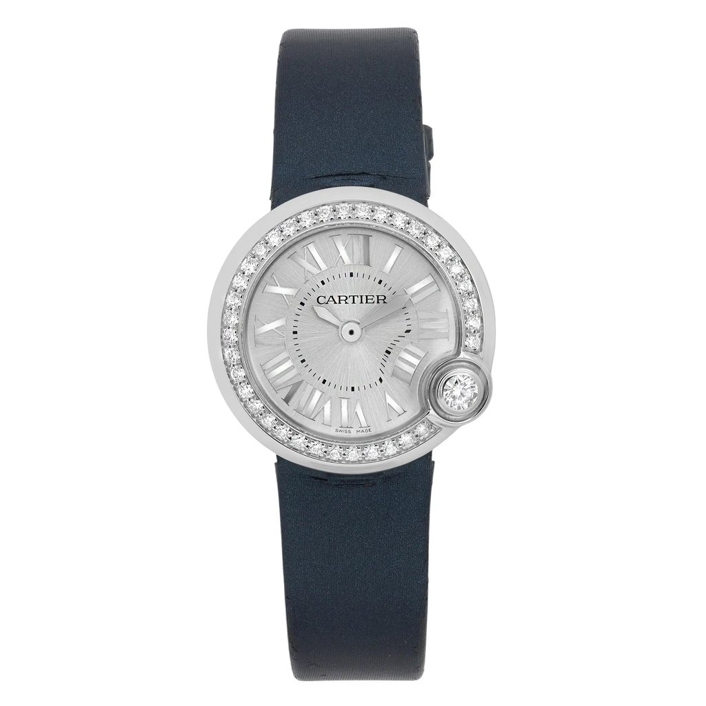 An image of a pre-owned Cartier Ballon Blanc De Cartier 26MM Diamonds Silver Dial Quartz Watch W4BL0002 positioned centrally and viewed from a top-down angle. The watch features a round face with a silver dial, surrounded by a bezel adorned with small diamonds. The time is indicated by Roman numerals and sleek hands. The watch is attached to a dark, smooth strap, and the image is captured at a close distance, highlighting the intricate details of the timepiece.