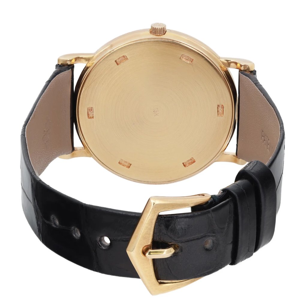 An image of a pre-owned wristwatch showcasing the back view at a close angle. The watch features a round gold case with a visible crown at the top. It is paired with a black leather strap, and the gold clasp is prominently displayed in the foreground. The watch is positioned upright, providing a clear view of the back and clasp details.