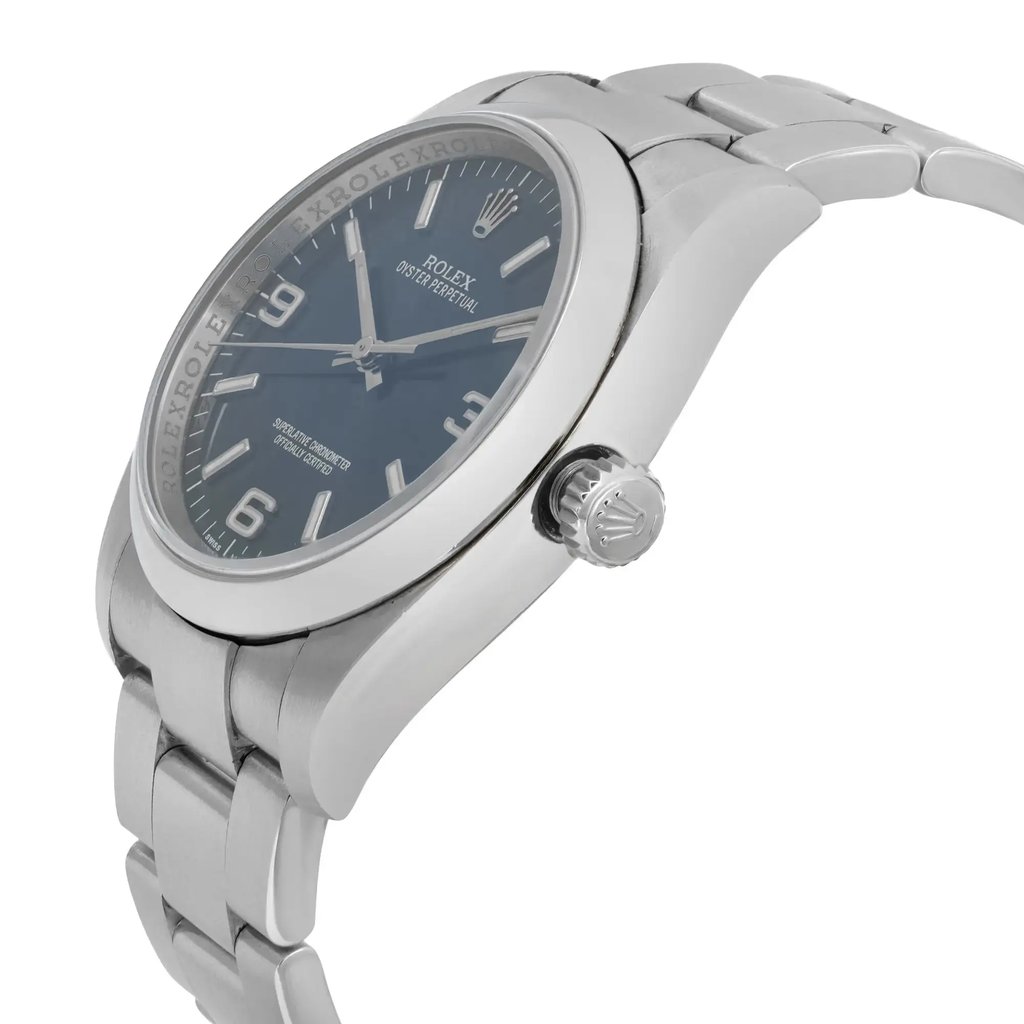 An image of a pre-owned wristwatch shown from a side profile view, highlighting the crown. The watch has a metal bracelet and a dark dial with visible hour markers and hands. The angle captures the watch at a slight upward tilt, showcasing its sleek design. The distance allows for a clear view of the crown and the watch face details.