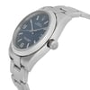 An image of a pre-owned wristwatch shown from a side profile view, highlighting the crown. The watch has a metal bracelet and a dark dial with visible hour markers and hands. The angle captures the watch at a slight upward tilt, showcasing its sleek design. The distance allows for a clear view of the crown and the watch face details.
