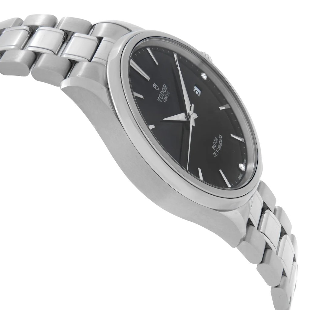 An image of a pre-owned Tudor men's wristwatch taken from a low angle, showcasing the side profile and partial view of the face. The watch features a stainless steel bracelet and a black dial with a date indicator. The perspective highlights the sleek design and craftsmanship of the timepiece.
