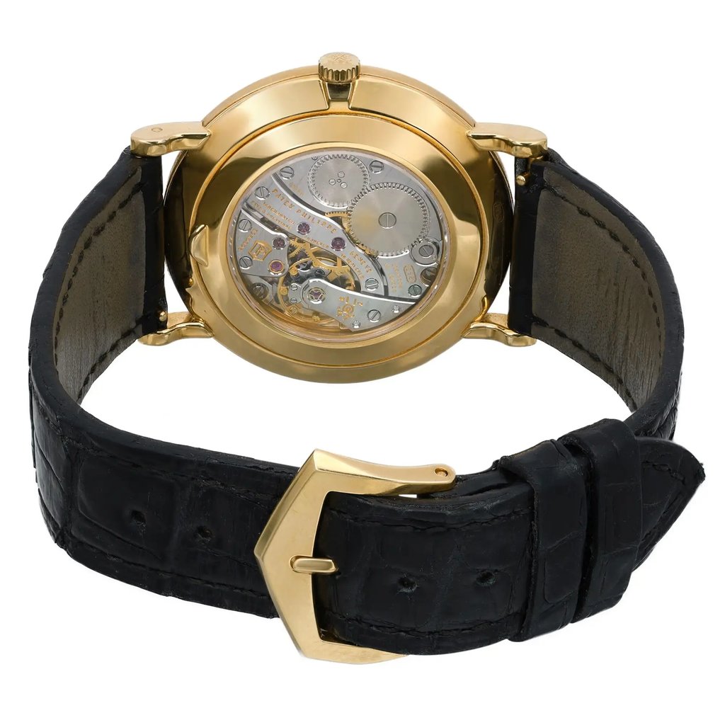 An image of a pre-owned wristwatch showcasing the back view. The focus is on the intricate, exposed mechanical movement within a polished gold case. The watch is positioned upright with the black leather strap partially open and the gold-tone clasp visible. The close-up angle highlights the detailed craftsmanship of the watch's inner workings.