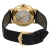 An image of a pre-owned wristwatch showcasing the back view. The focus is on the intricate, exposed mechanical movement within a polished gold case. The watch is positioned upright with the black leather strap partially open and the gold-tone clasp visible. The close-up angle highlights the detailed craftsmanship of the watch's inner workings.