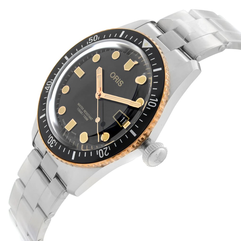An image of a wristwatch in a side profile view, showcasing the crown prominently. The watch features a metallic strap and a black dial with gold markers and hands. The bezel has a gold edge with minute markings. The photograph is taken at a slight angle to highlight the watch's design details, with a close-up distance emphasizing the craftsmanship. The watch is a display model.