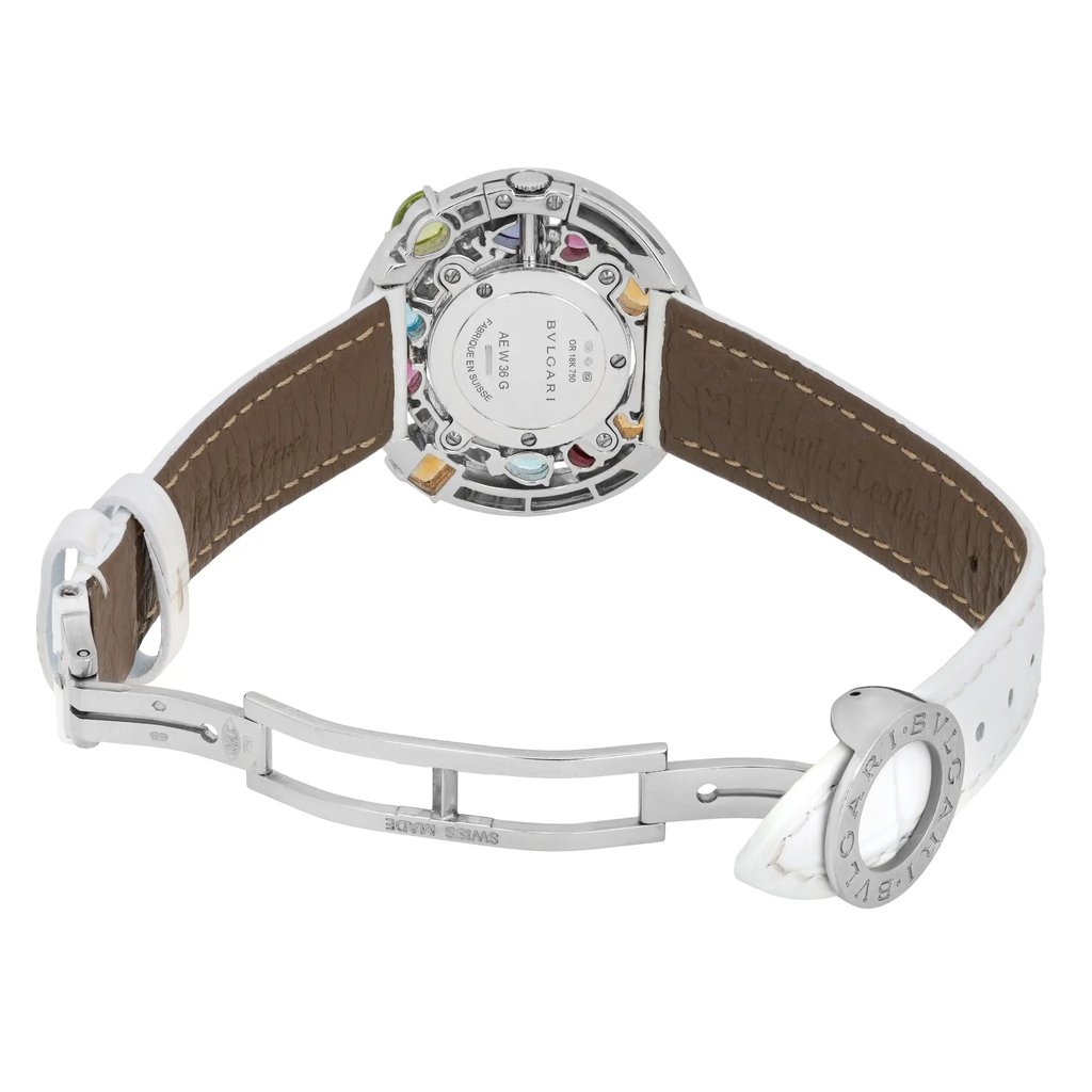 An image of a pre-owned Bvlgari women's wristwatch taken from a slightly elevated rear angle, showcasing the back of the watch case and the open clasp. The focus is on the intricate details of the watch's back, including visible colored accents around the case. The white leather strap is partially visible, with the clasp positioned in the foreground, highlighting its metallic finish. The image captures the watch from a close distance, emphasizing the craftsmanship and design elements.