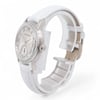 An image of a pre-owned Audemars Piguet women's wristwatch, viewed from a slightly elevated angle, showcasing the front and side. The watch features a round face with a diamond-studded bezel and a white leather strap. The watch is positioned to highlight its elegant design details, with the crown on the right side visible. The photograph is taken at a close distance, emphasizing the luxurious elements of the timepiece.