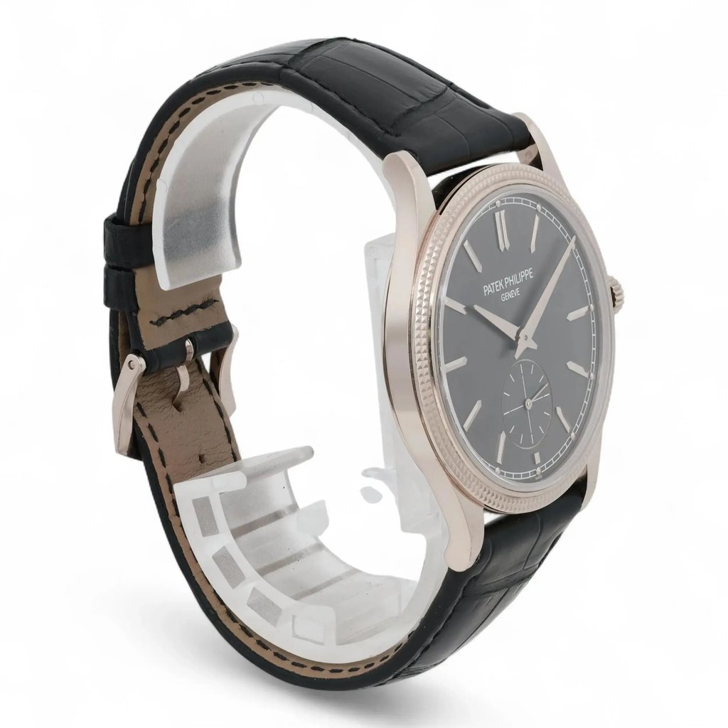 An image of a pre-owned men's Patek Philippe wristwatch positioned at a slight angle, showcasing the side and part of the face. The watch has a sleek black leather strap and a polished metal case. The angle highlights the watch's elegant design and craftsmanship, with the focus on the watch face and its detailed markers. The distance is close, providing a clear view of the watch's features.
