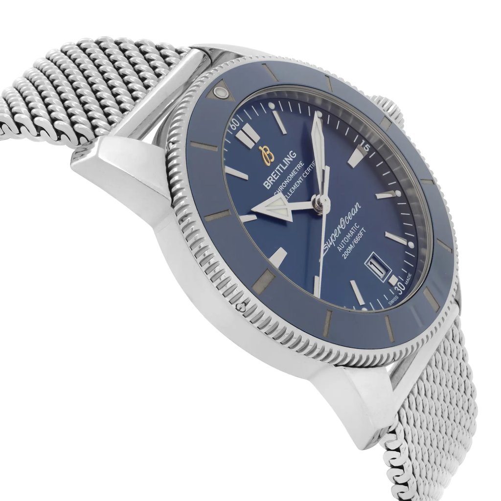 An image of a pre-owned Breitling men's wristwatch in a side profile view opposite of the crown, showing a sunburst blue dial and matching blue bezel. The watch features a round stainless steel case and a stainless steel mesh bracelet. The close-up angle provides a clear view of the watch's condition and luxurious diver-style details. The watch is pre-owned and has light signs of wear and scratches.