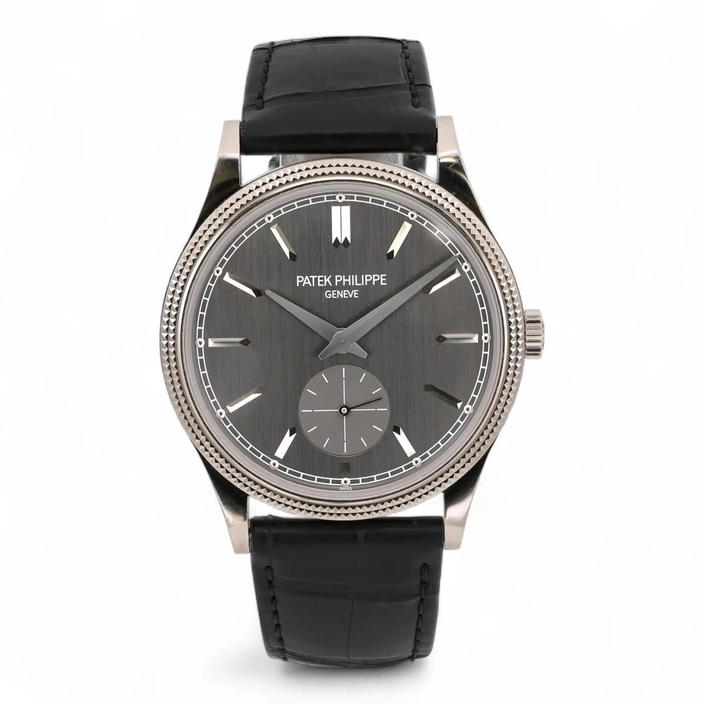 An image of a pre-owned Patek Philippe Calatrava 18K White Gold Gray Dial Men Watch 6119G-001 shown from a straight-on angle. The watch features a gray dial with silver hour markers, a small subdial, and sleek hands. It has a textured silver bezel and a black leather strap. The photograph captures the watch in close-up, highlighting its elegant design and intricate details. Pre-owned in excellent condition. Comes with Patek travel pouch and paper. No manuals just papers. Recently serviced. The movement is calibrated and keeps time well.