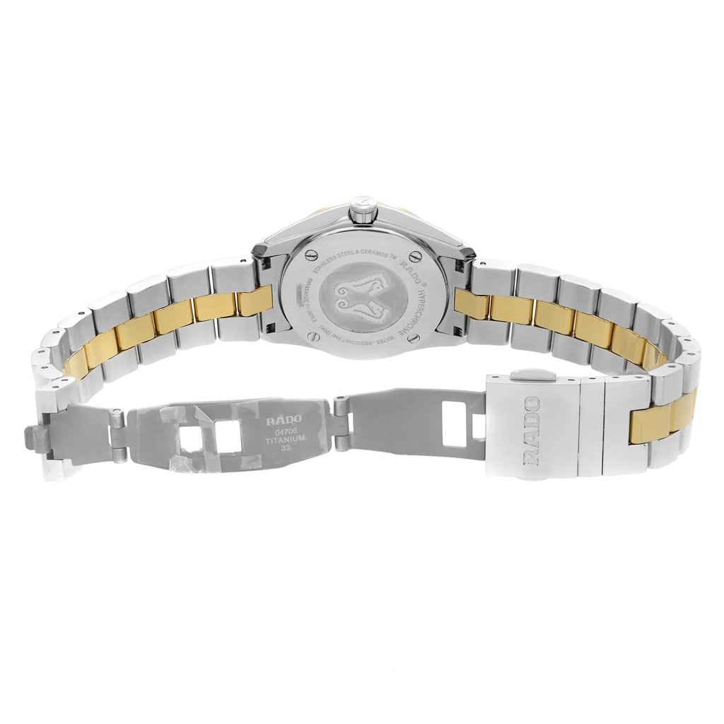 An image of a wristwatch showing the back view with an open clasp. The watch is positioned horizontally, displaying the stainless steel and gold-toned bracelet in full view. The camera angle is directly from behind, capturing the engraved details on the watch's case back. The distance is close-up, focusing on the watch's design elements and brand markings.