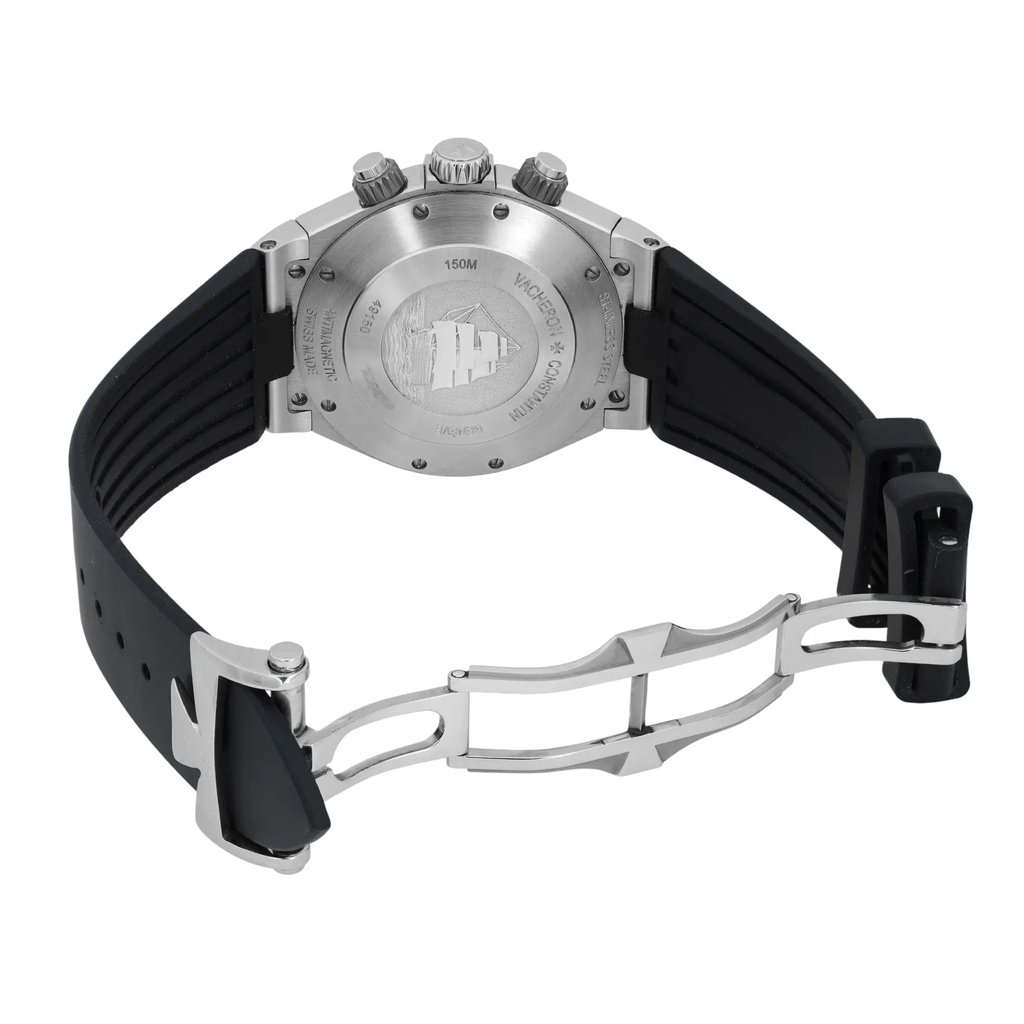 An image of a pre-owned Vacheron Constantin men's wristwatch, captured from a rear angle. The focus is on the stainless steel case back, showcasing engraved details and a decorative emblem. The watch is positioned at a slight angle from the left, highlighting the black rubber strap and the open clasp. The image is taken from a moderate distance, clearly displaying the watch's features and condition.