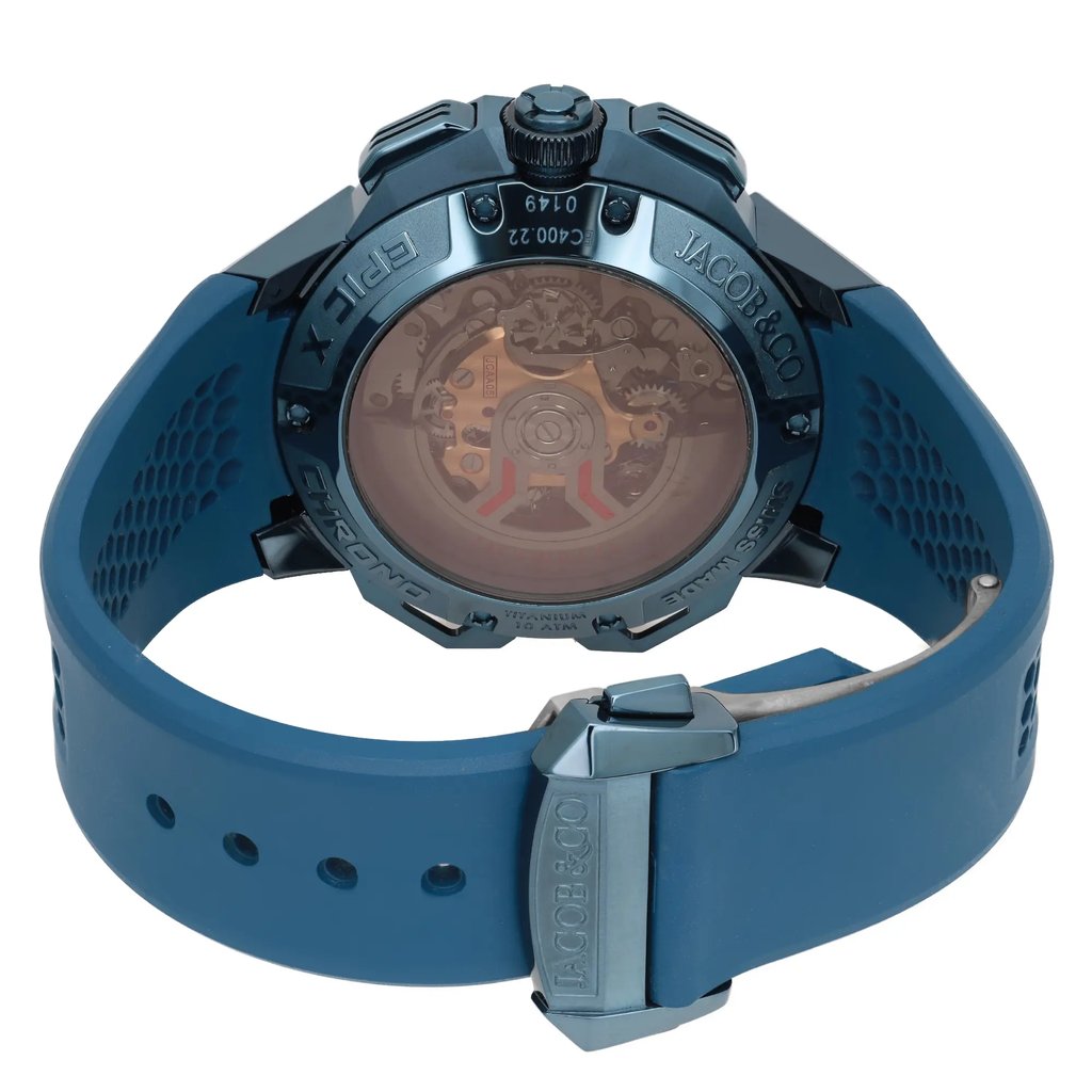 An image of a pre-owned wristwatch viewed from the back, showcasing the closed clasp. The watch is positioned at a slight angle, allowing a clear view of the intricate mechanical details through the transparent case back. The blue strap with a honeycomb pattern and metallic clasp is prominently displayed in the foreground. The brand name is visible on the clasp, adding to the detailed presentation of the watch's features.