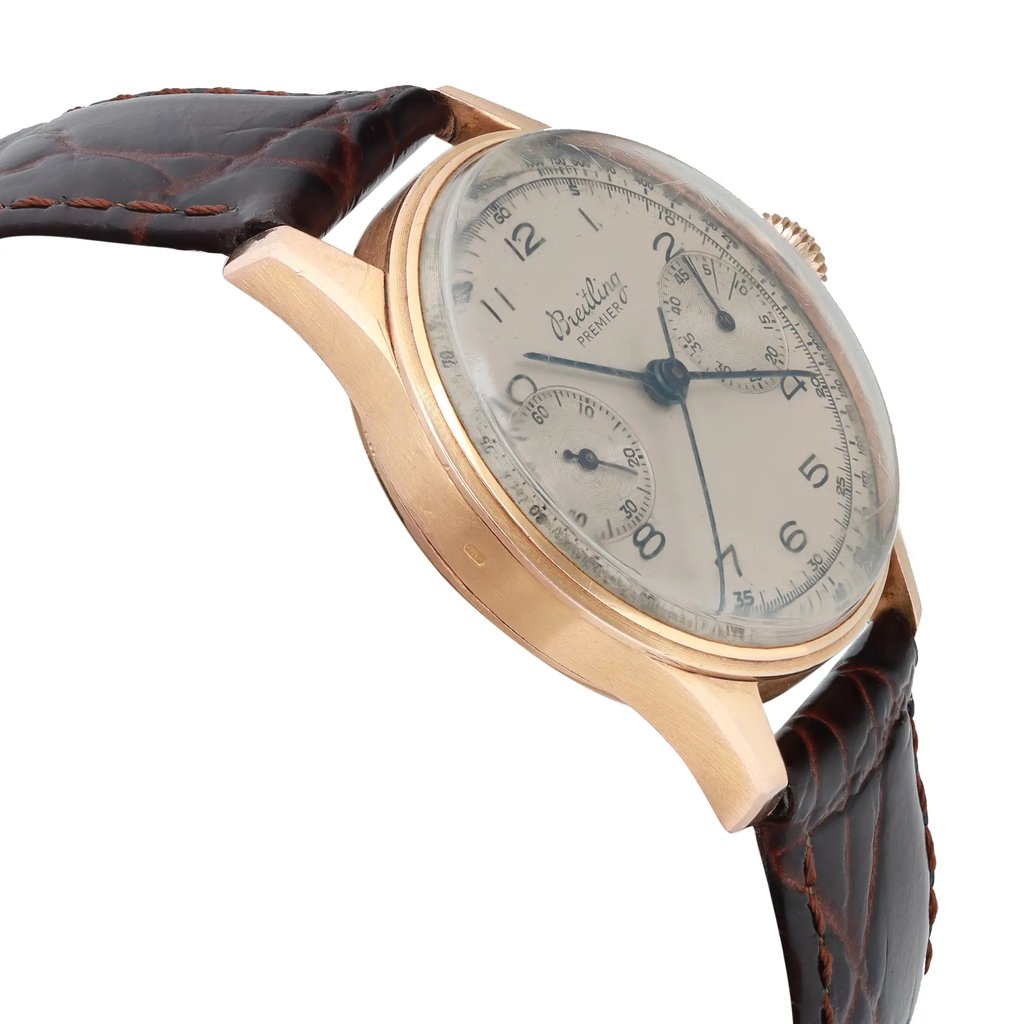 An image of a pre-owned Breitling men's wristwatch in a classic style, showcasing a side profile view opposite of the crown. The watch features a round rose gold case and a silver dial with patina, along with a small seconds subdial. Visible scratches can be seen on the crystal, and it is fitted with an aftermarket dark brown leather band. The view is at a close distance, emphasizing the angle and condition of the watch.