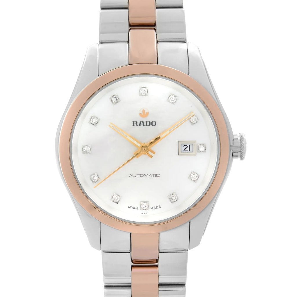 An image of a wristwatch showing a front close-up shot of the watch face. The timepiece features a polished stainless steel case with a rose gold bezel. The dial is mother-of-pearl with diamond hour markers and gold hands, and it includes a date window at the 3 o'clock position. The bracelet combines stainless steel and rose gold links for a refined look.