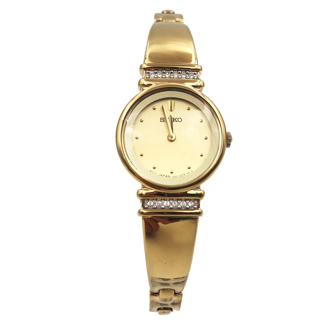 An image of a Wristwatch by Seiko. This Pre Owned item is designed for Women, featuring a Dress/Formal style. It has a Quartz movement and an Analog display with a Gold dial color. The indices include 12-Hour Dial,Non-Numeric Hour Marks,Round Indexes. The band is made of Stainless Steel and the case is made of Stainless Steel. The watch has a Round shape with a case size of 21 mm and a case thickness of 6 mm.