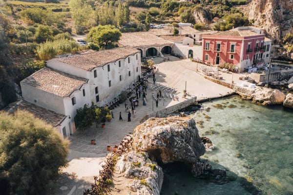 Tonnara di Scopello, Sicily — a wedding gathered on the stone quay of the historic tuna fishery above a turquoise cove