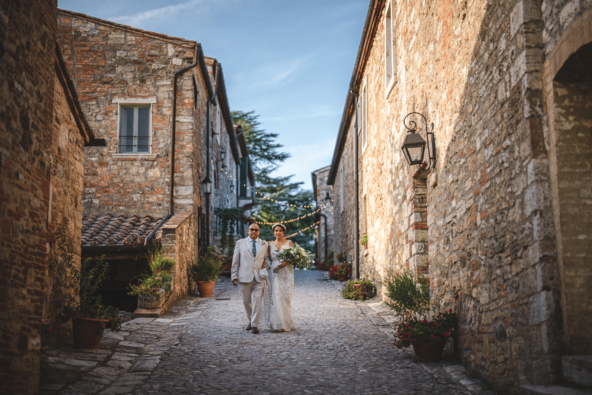 Borgo Laticastelli, Rapolano Terme: a couple walking down the stone lane between the medieval houses of the hamlet
