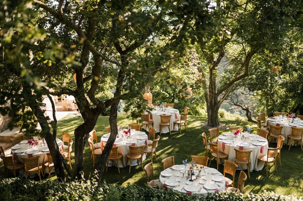 Castello di Vicarello — round wedding dinner tables set under shade trees in a Tuscan garden