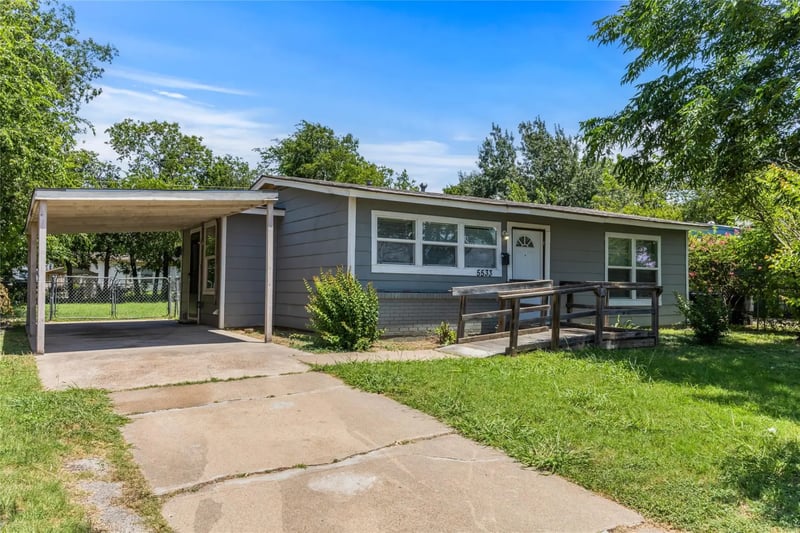 Single-story grey clapboard home with an attached carport and a wide concrete driveway in east Fort Worth, Texas