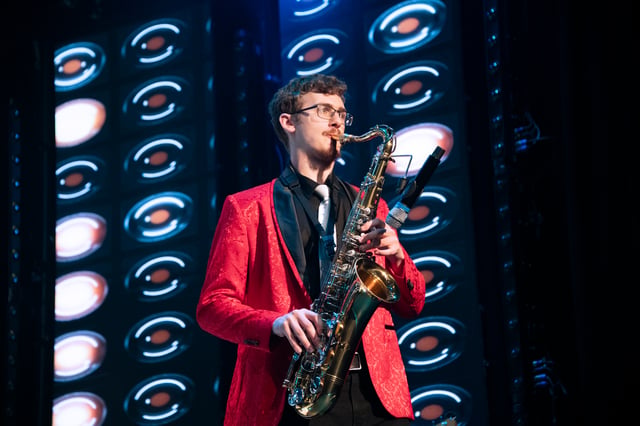 Seth Wright playing saxophone in a red sequin jacket