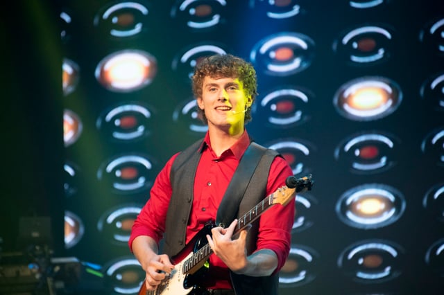 Orson Wright playing electric guitar in a red shirt and vest