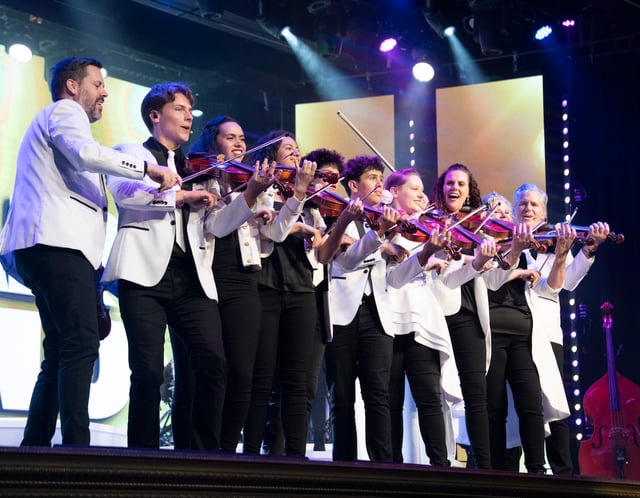 The Duttons in white jackets playing violins in the famous violin lineup