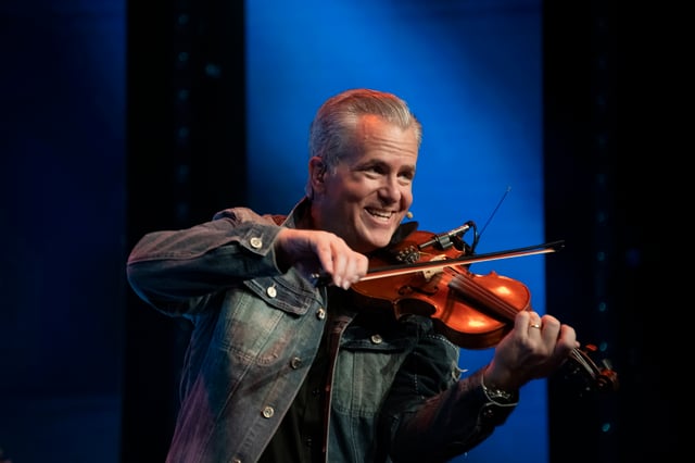 Timothy Dutton playing fiddle in a denim jacket