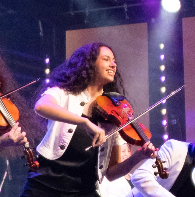 Selena Dutton smiling as she plays the violin