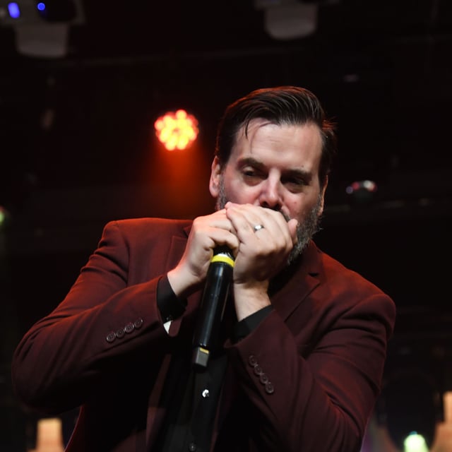 Joshua Dutton playing harmonica into a microphone