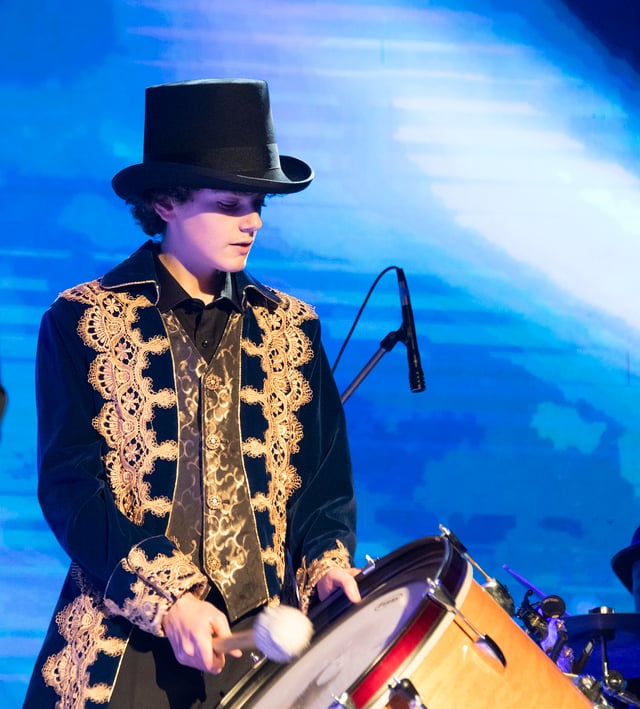 Marcus Wright playing a drum in a top hat and gold-trimmed pirate coat