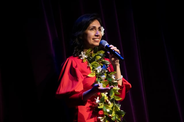 Bella Dutton singing in a red dress and flower lei