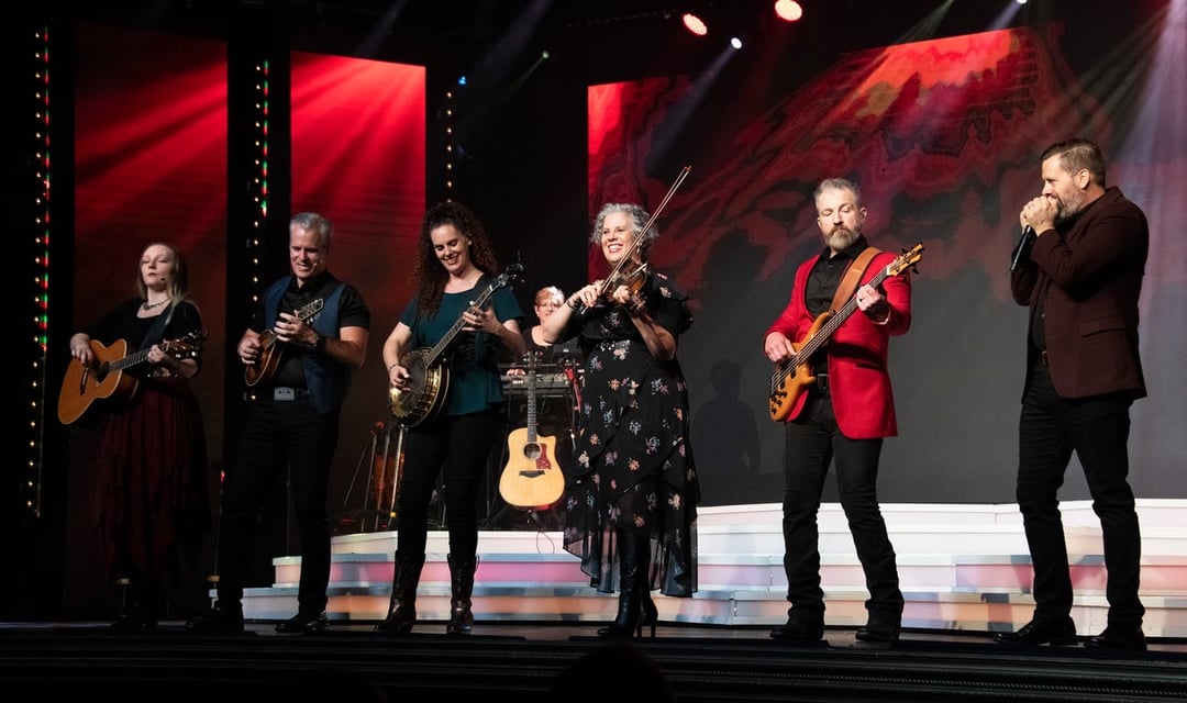 The Duttons playing guitars, banjo and fiddle under red stage lights