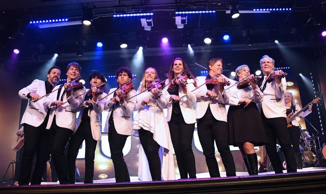 The Duttons in white jackets playing fiddles together